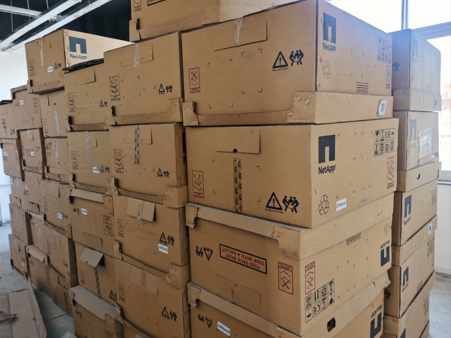 Stacked NetApp shipping cartons — supplied warehouse photograph, digitally edited